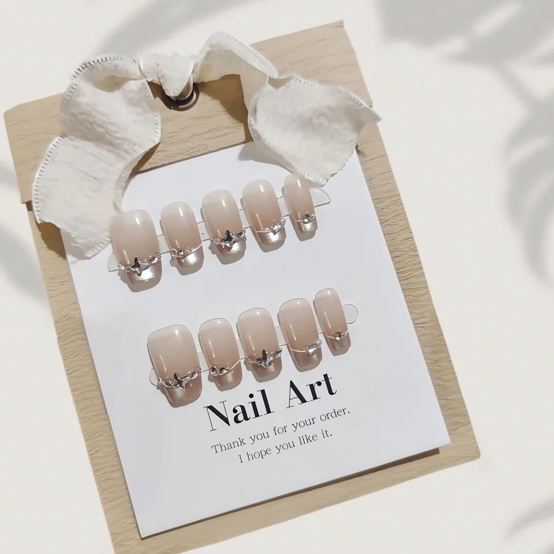 Faux ongles French avec strass papillon et effet œil de chat