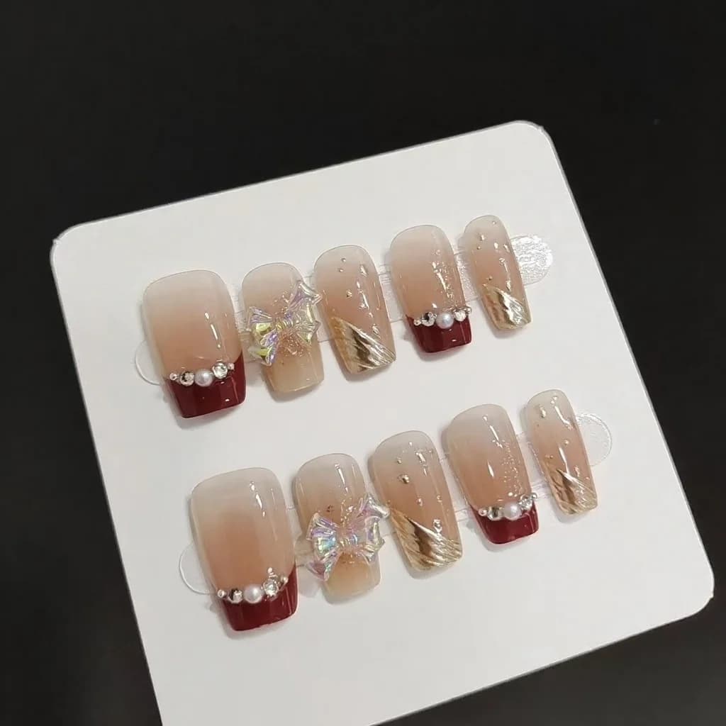 Faux ongles courts French manucure paillettes dorées et nœud