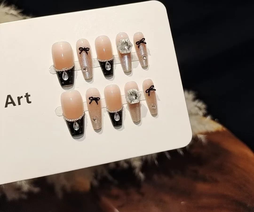Faux ongles pêche et chocolat noir avec nœud, design paillettes effet œil de chat