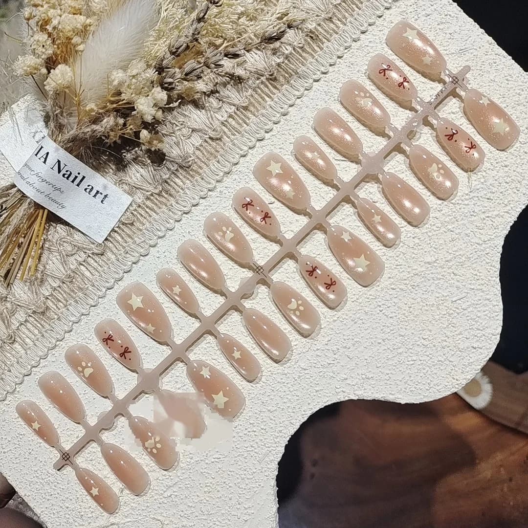 Faux ongles nude rose effet œil de chat avec nœud et perles étoiles
